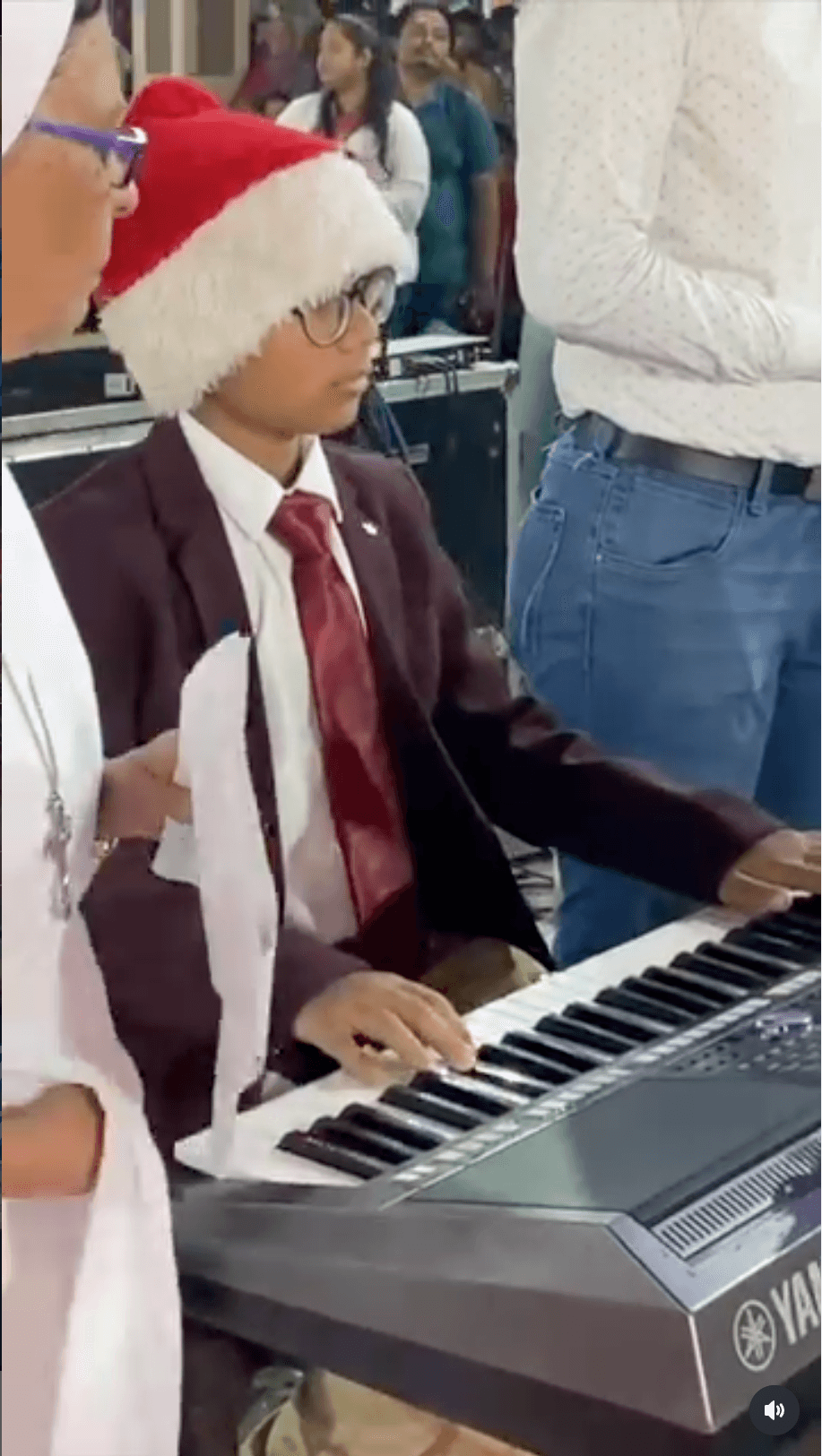 Bala at a keyboard wearing a Santa hat, with other people standing beside him.